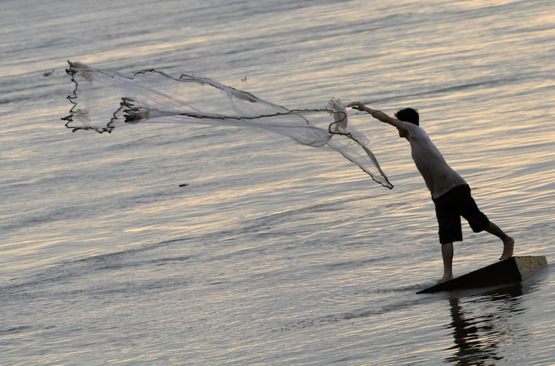 A man casts a fishing net on the bank of the Mekong river in Phnom Penh December 8, 2011.
