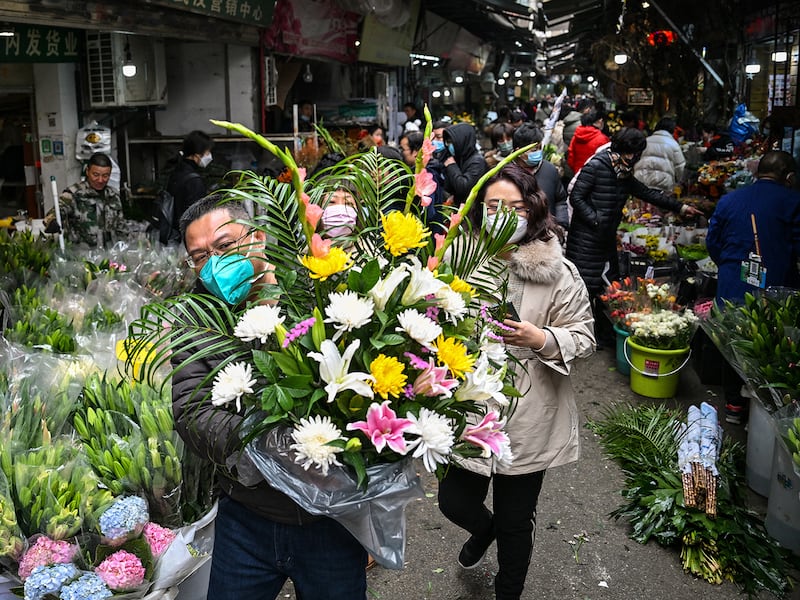 A man holds a flower arrangement at a flower market in Wuhan, China, Jan. 21, 2023, ahead of the Lunar New Year.
